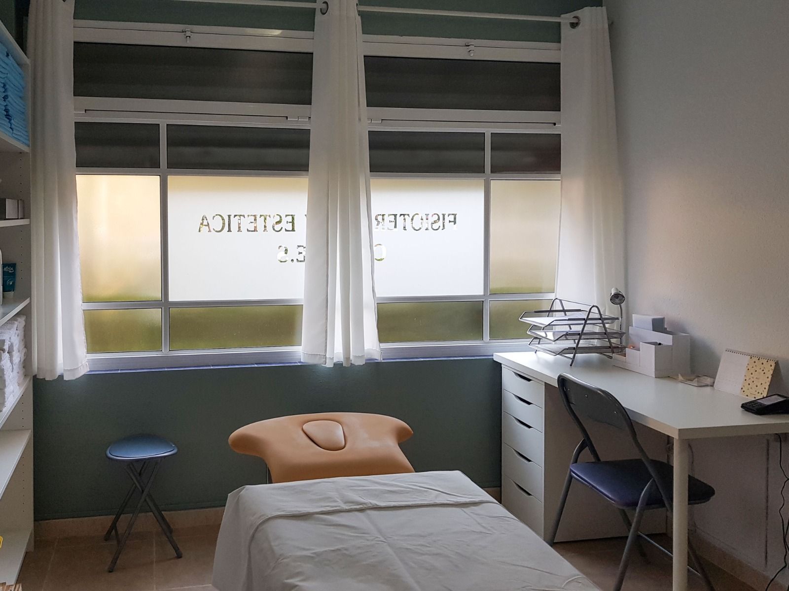 Sala de fisioterapia de CEFYES: camilla, escritorio y ventana con el rótulo del centro